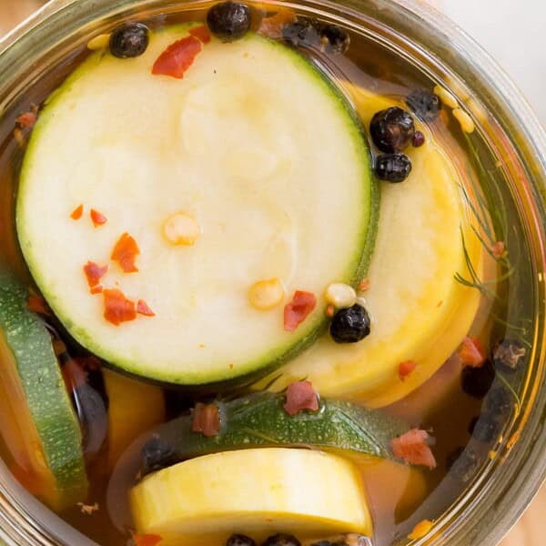 sweet and spicy zucchini pickles in a glass jar with the lid off