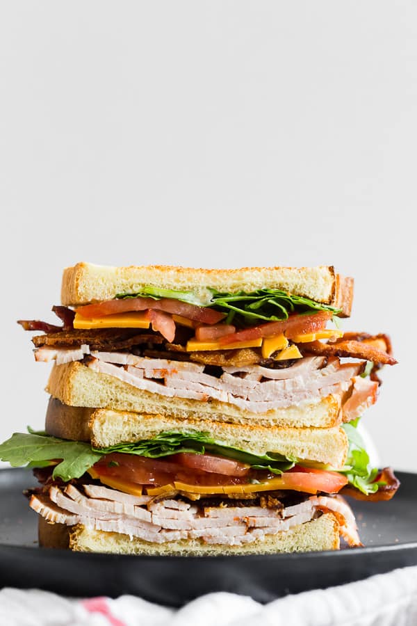 Sandwich halves stacked on top of each other and filled with turkey, lettuce, bacon and cheese.