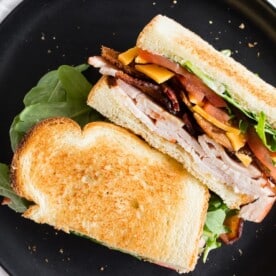 This turkey and cheese BLT sandwich is the perfect back to school sandwich. It combines lightly toasted bread with a homemade garlic basil mayonnaise, sliced turkey, sharp cheddar cheese, crispy bacon, sliced tomato and baby arugula. It's flavorful, easy to make and a step above your everyday bagged lunch sandwich.