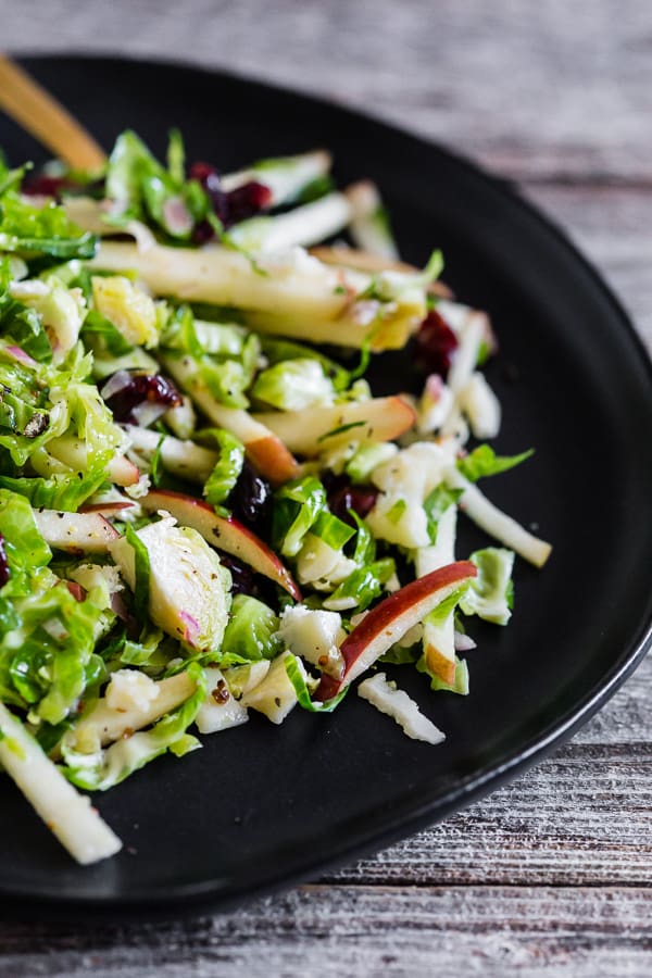 Tangy Brussels Sprout Apple Slaw on a black plate.