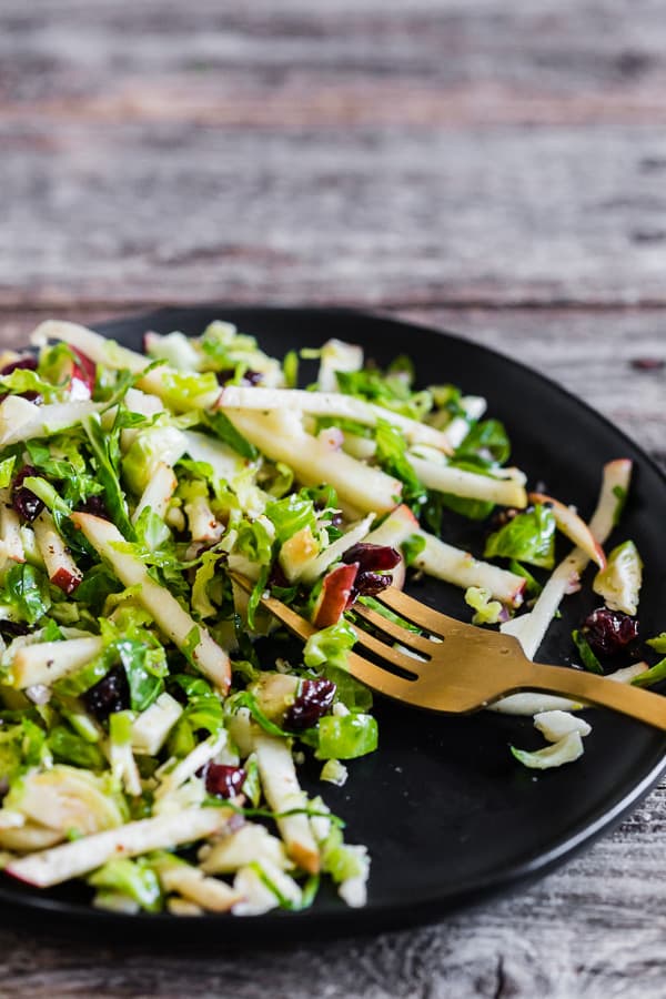 A fork grabbing a bite of Tangy Brussels Sprout Apple Slaw.