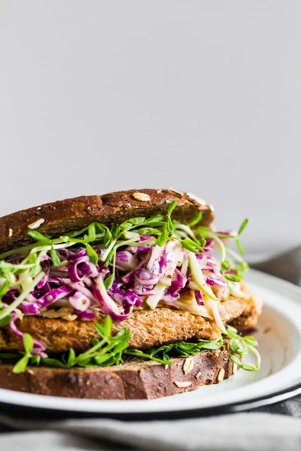 This crispy chicken sandwich with cabbage apple slaw takes the flavors of fall and puts them into a sandwich. It’s a perfectly cooked crispy chicken cutlet topped with smoked Gouda cheese, pea shoots, and a homemade tangy red cabbage apple slaw. You’ll love this killer sandwich.