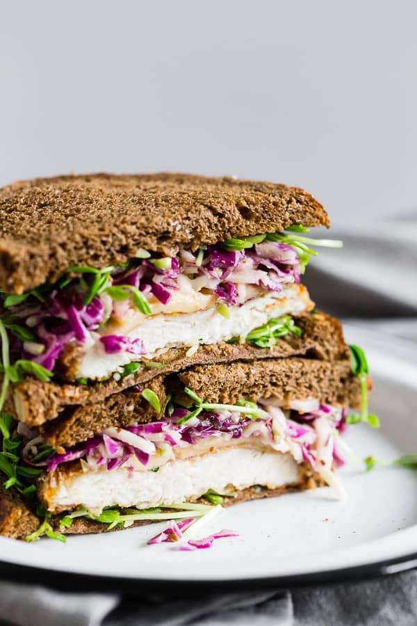 This crispy chicken sandwich with cabbage apple slaw takes the flavors of fall and puts them into a sandwich. It’s a perfectly cooked crispy chicken cutlet topped with smoked Gouda cheese, pea shoots, and a homemade tangy red cabbage apple slaw. You’ll love this killer sandwich.