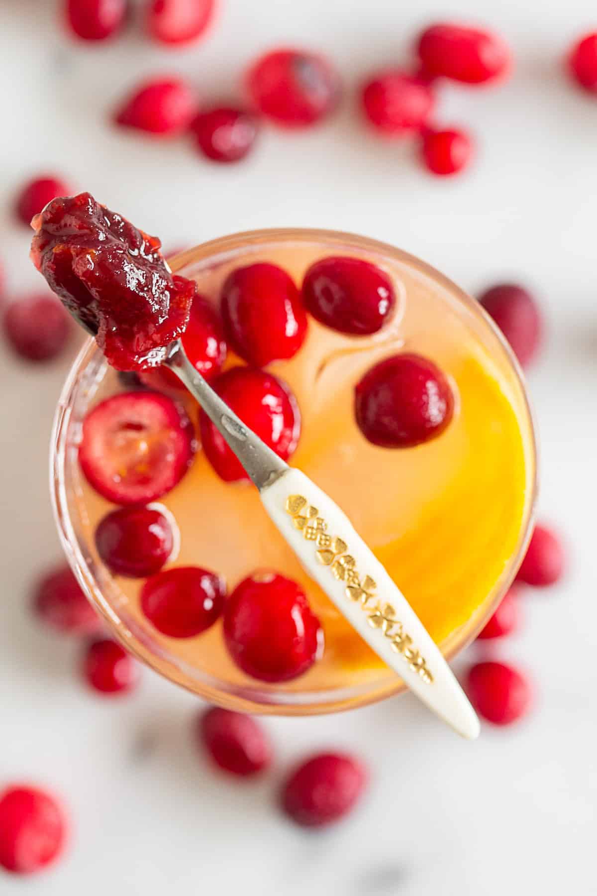 Cranberry Gin Fizz in a glass with a tiny spoon served on top with extra cranberry sauce. 