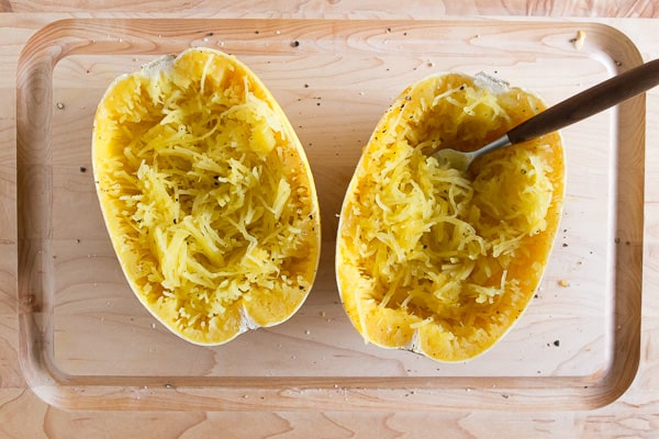 two spaghetti squash halves shredded on a cutting board