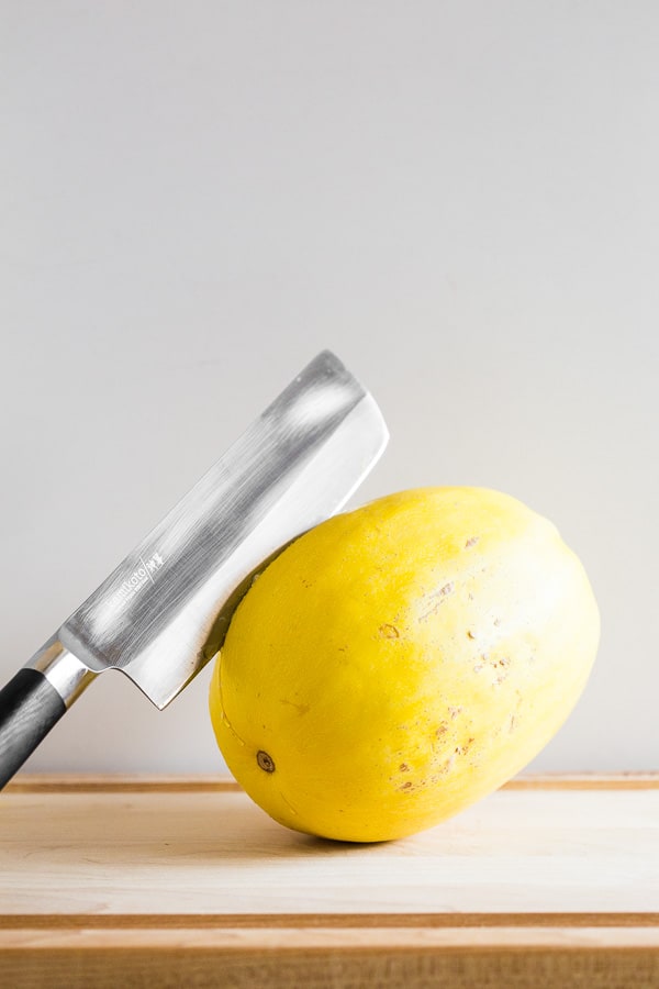 spaghetti squash on a cutting board with a knife in the flesh
