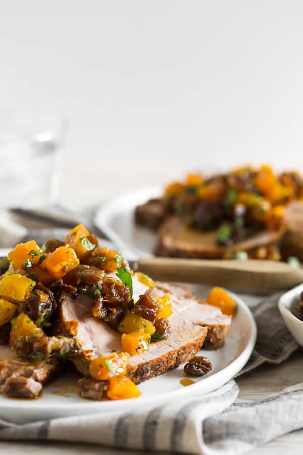 This roast pork loin with dried fruit compote is packed full of flavor and the compote is super easy to make. Roast Pork Loin with Dried Fruit Compote on a plate with a fork.