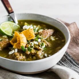This Instant Pot pork chili verde is packed full of tomatillos, cilantro, diced green chiles, fork-tender pork shoulder, and white beans. It's perfect for cold snowy days and tastes great when topped with Cotija cheese, cilantro, and crispy corn chips.