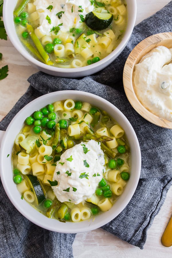 Spring Minestrone Soup with Lemon Whipped Ricotta in a white bowl. 