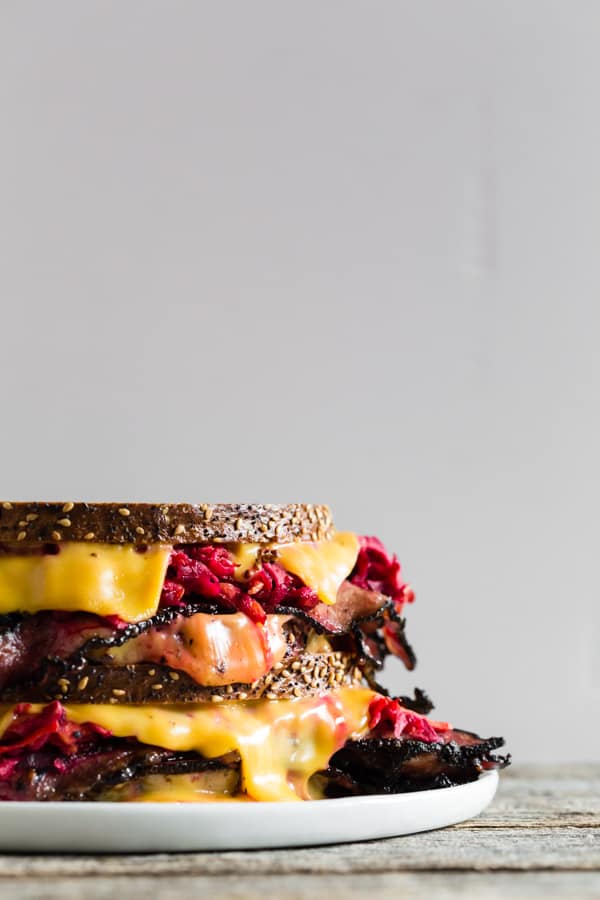 Grilled Pastrami Sandwich with Root Vegetable Slaw shown from the side to show melty cheese. 