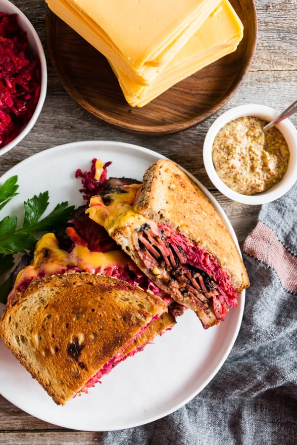 Grilled Pastrami Sandwich with Root Vegetable Slaw sliced on a plate. 