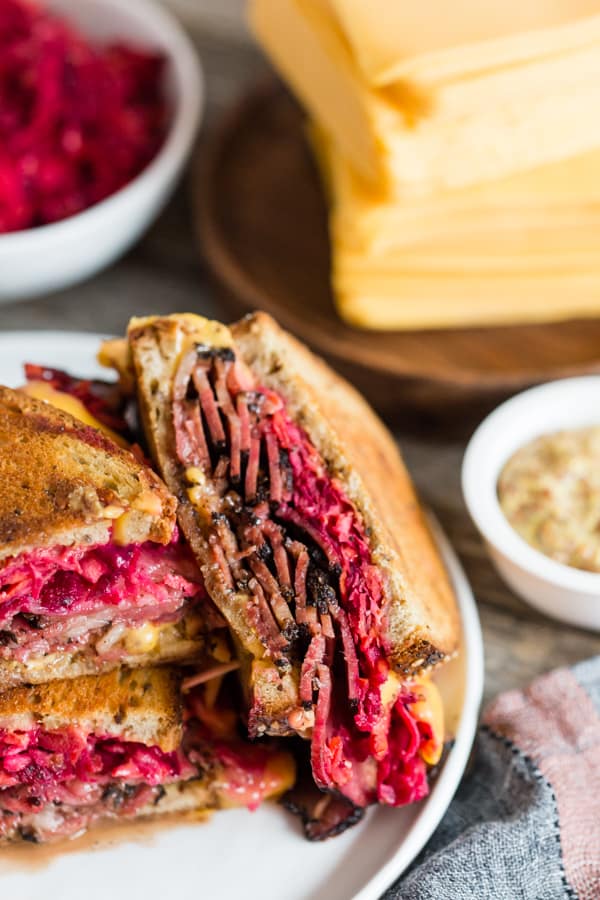 Grilled Pastrami Sandwich with Root Vegetable Slaw served on a white plate. 