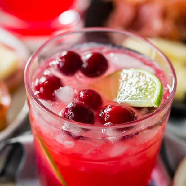 cranberry lemonade ginger beer cocktail in a glass garnished with lime and cranberries