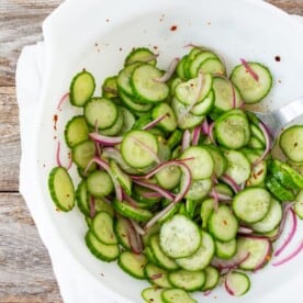 sliced cucumber salad with sliced red onion in a white bowl