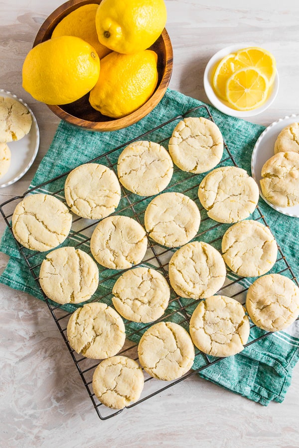 vanilla bean lemon sugar cookies on a tray with fresh lemon surrounding the cookies