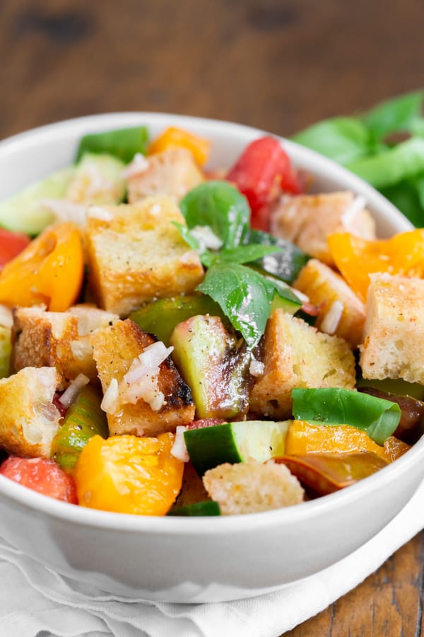 grilled sourdough panzanella salad in a white bowl with fresh basil