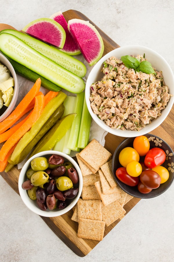 lemon herb tuna salad in a white bowl surrounded by fresh veggies and crackers