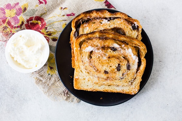 sliced cinnamon raisin sourdough bread sliced on a plate with butter