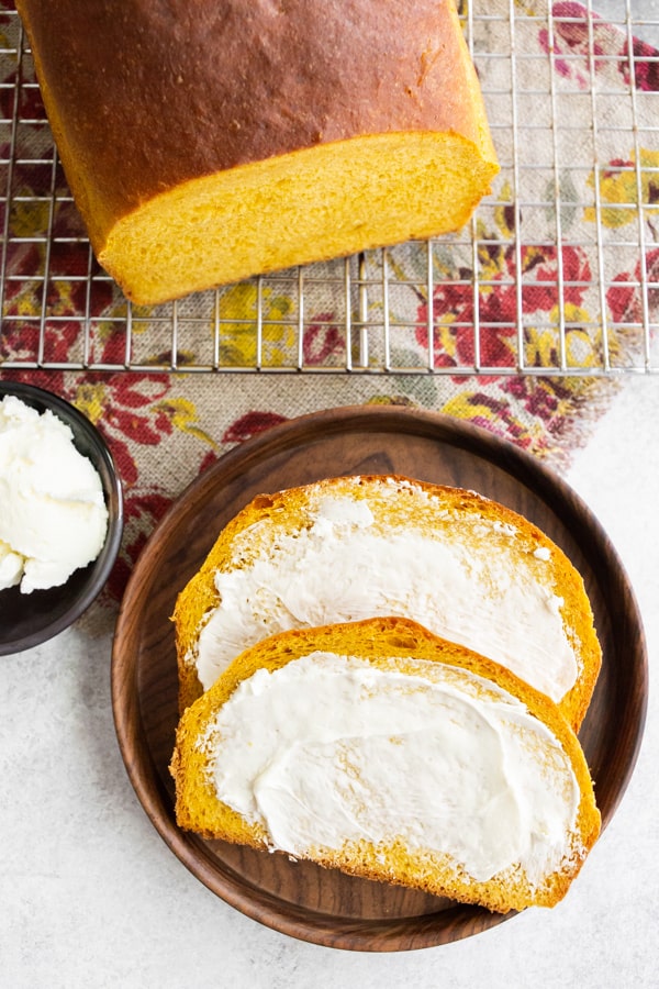 Pumpkin Yeast Bread sliced on a plate with butter