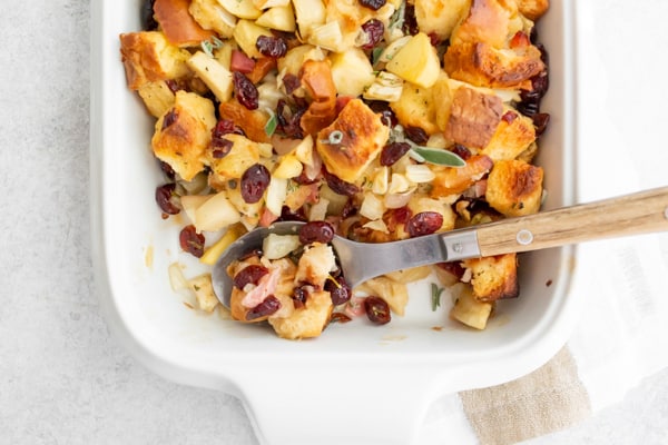 Pancetta apple fennel brioche stuffing in a casserole dish with spoon