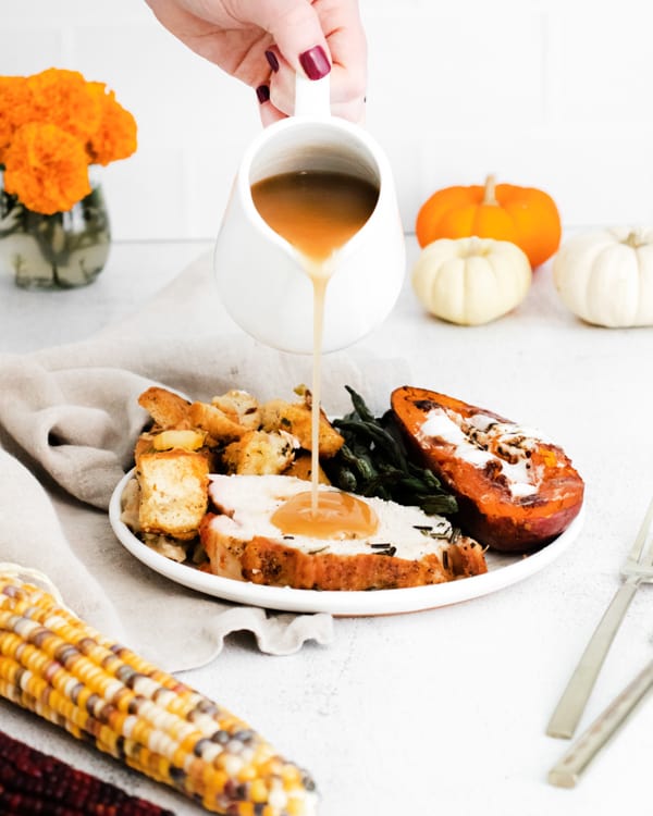 sheet pan thanksgiving on a plate with gravy being poured on
