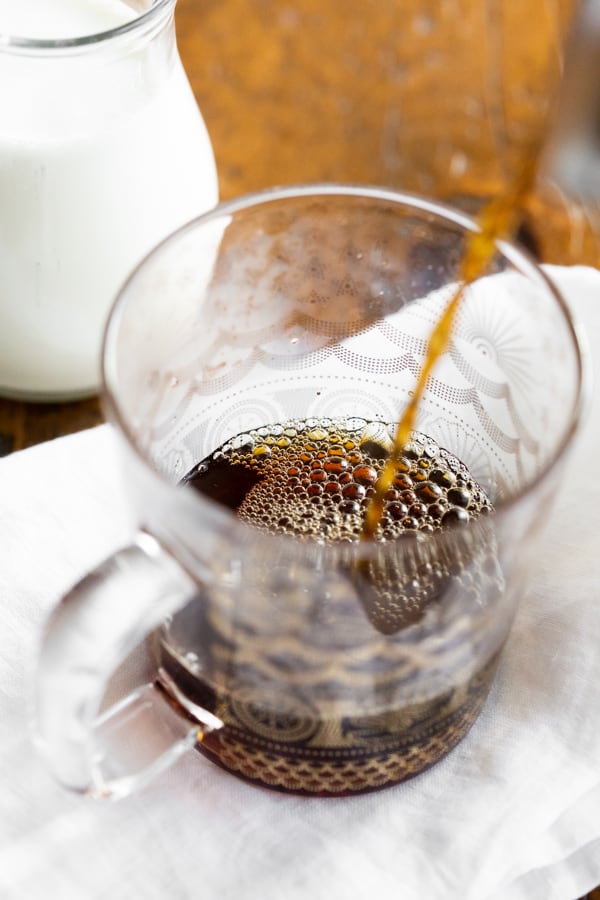 coffee being poured into a glass coffee mug