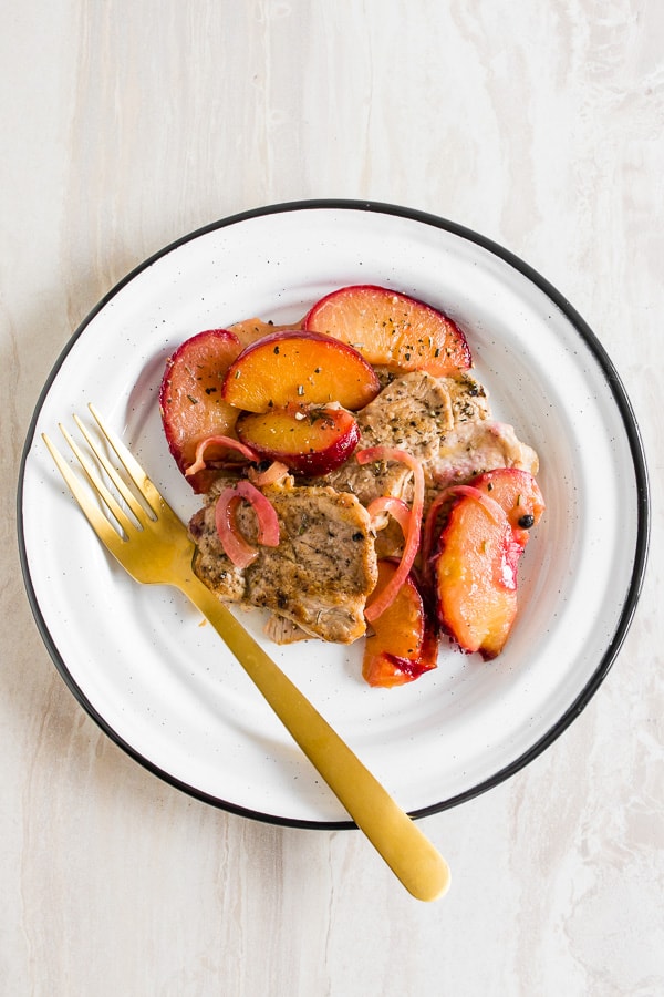 skillet pork tendrloin with plums shot from overhead on a plate with a fork.