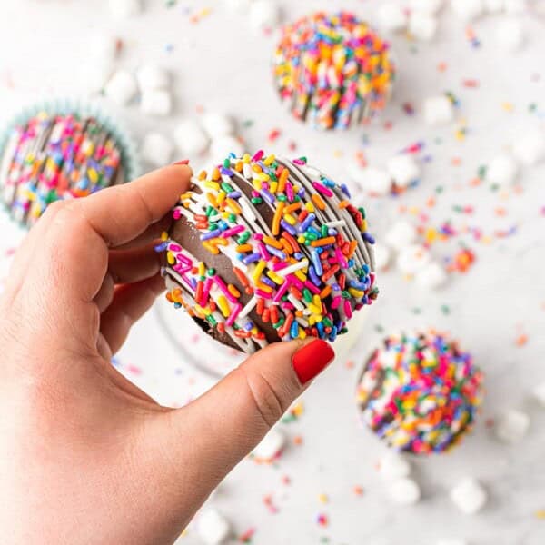 hand holding a chocolate strawberry funfetti hot chocolate bombs