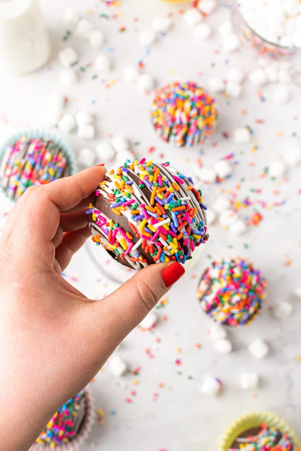 hand holding a chocolate strawberry funfetti hot chocolate bombs