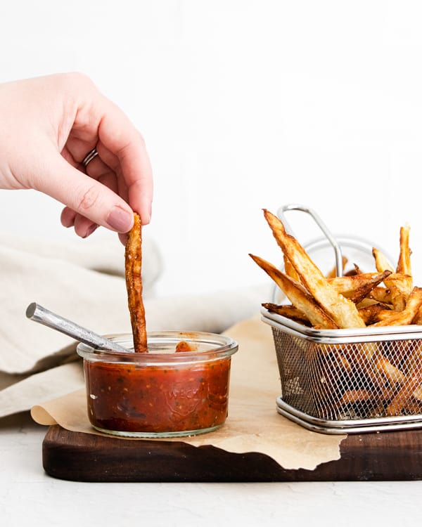 Garlic Parmesan Air Fryer French Fries being dipped into ketchup