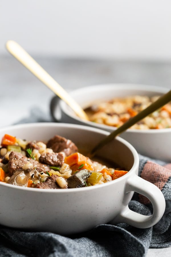 instant pot beef barley soup in a bowl with spoons