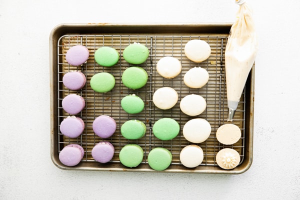 Easter egg macarons on a sheet pan cooling