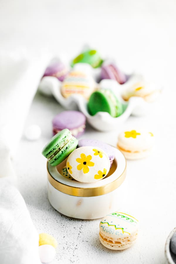 easter egg macarons in a white bowl.