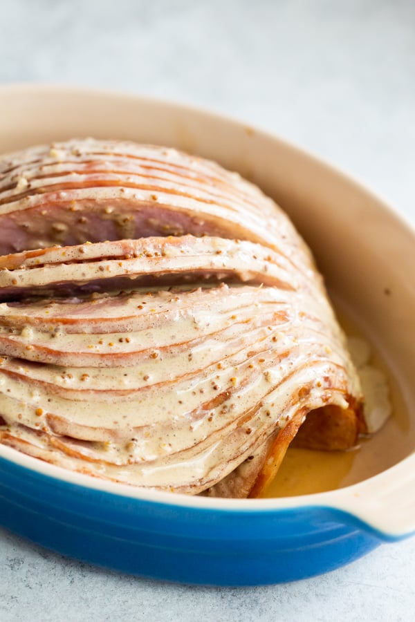 Unbaked spiral ham covered in glaze in a baking dish.