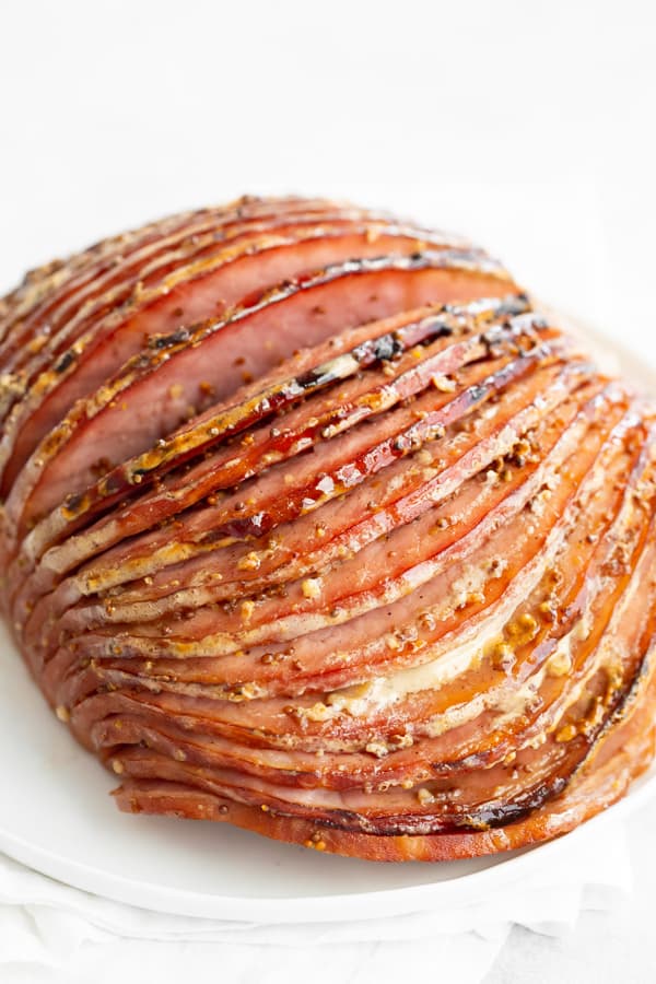 Honey Mustard Baked Ham with spiral slices on white plate.