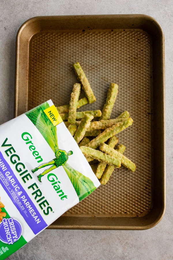 frozen veggie fries being poured onto a sheet pan.