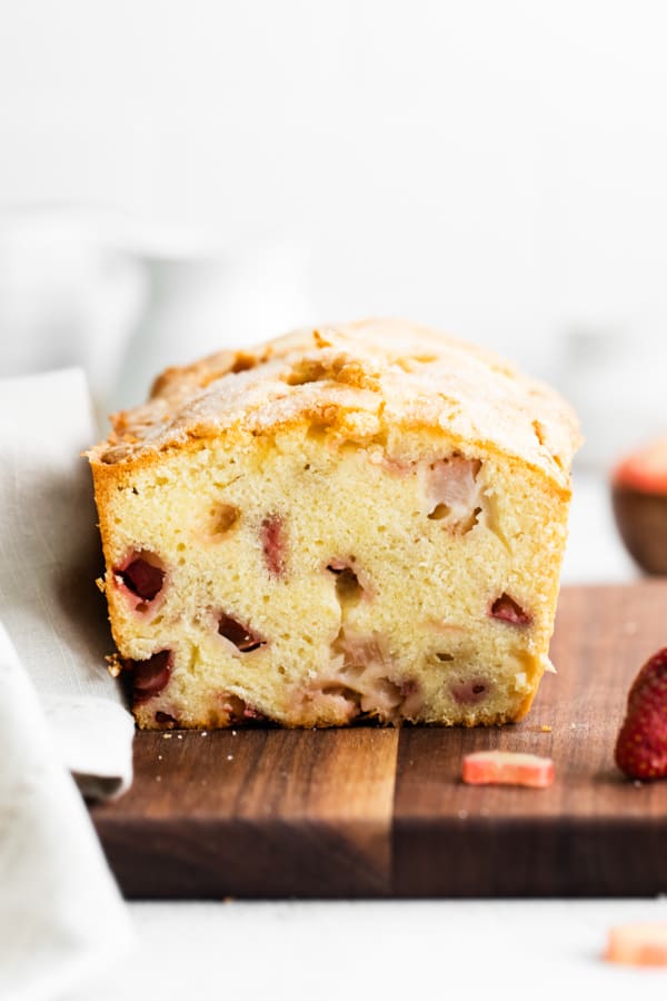 sliced strawberry rhubarb pound cake on a wooden cutting board.