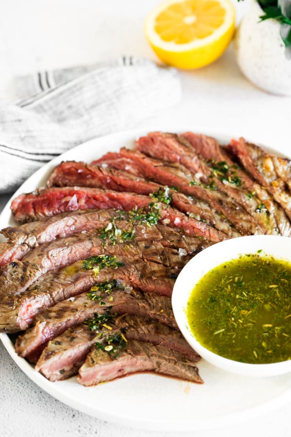 sliced chimichurri flank steak served with chimichurri sauce. 