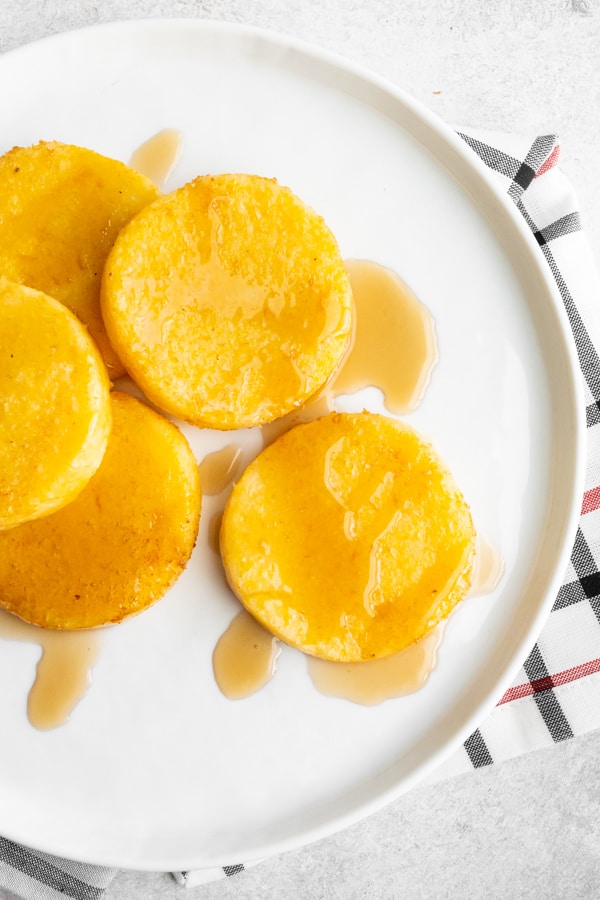 fried cornmeal mush on a plate with maple syrup. 