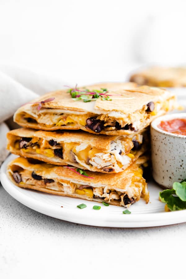 stacked sheet pan chicken quesadillas on a ceramic plate.