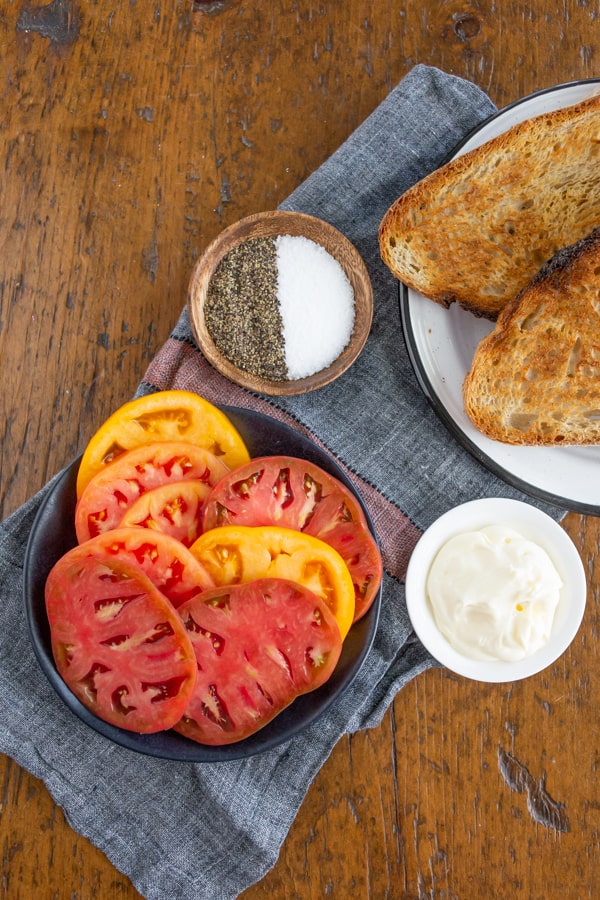 Ingredients for a tomato sandwich on a table.