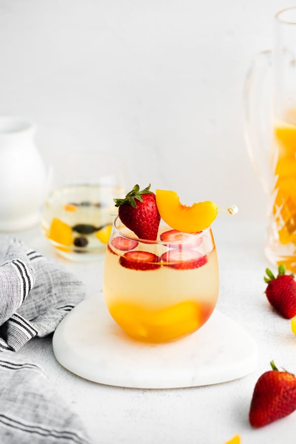 white wine peach sangria in a pitcher and in a serving glass.