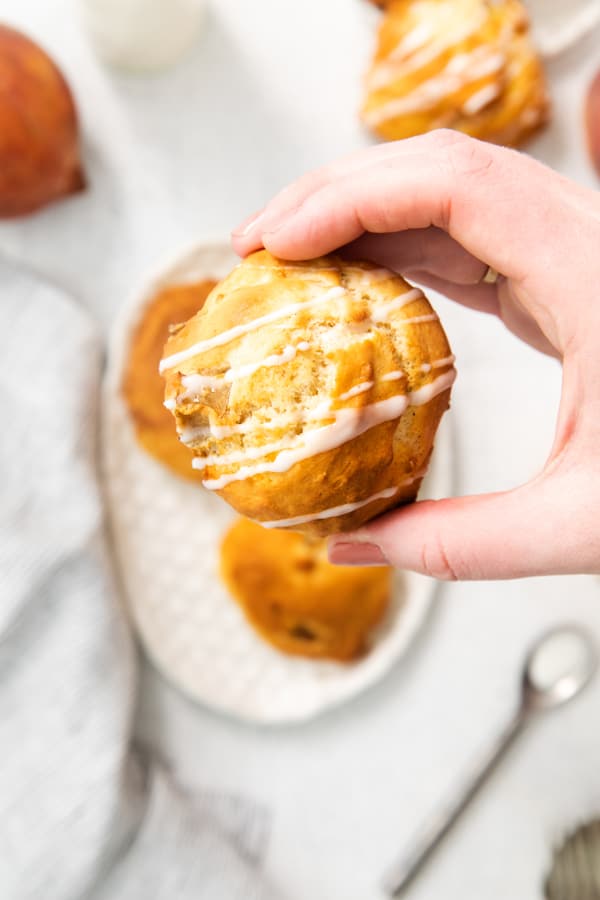 a hand holding air fryer peach fritters.