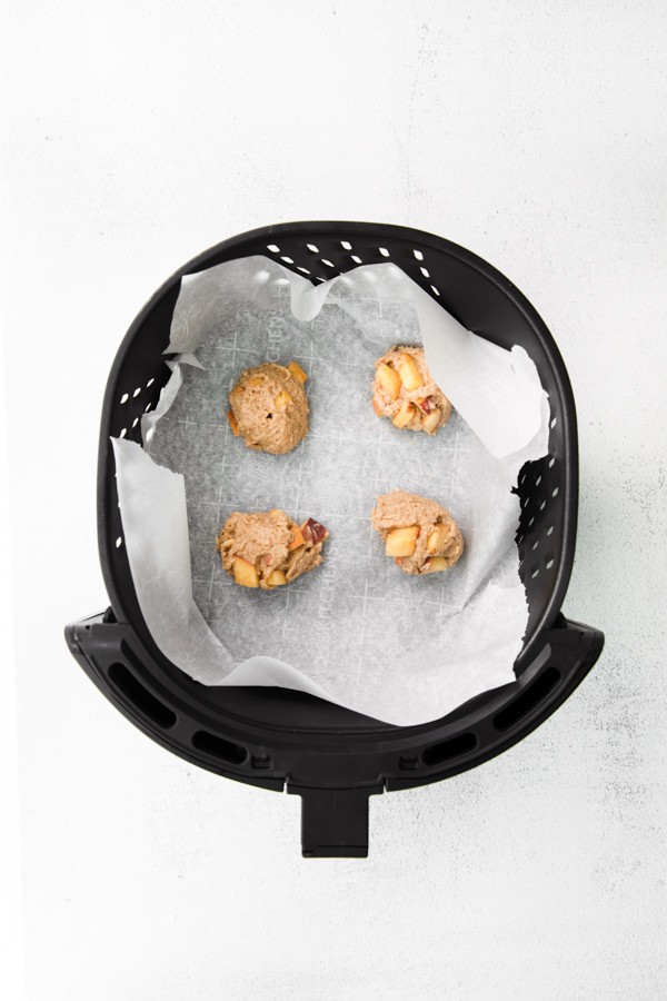air fryer peach fritters sitting in the air fryer waiting to be air fried. 