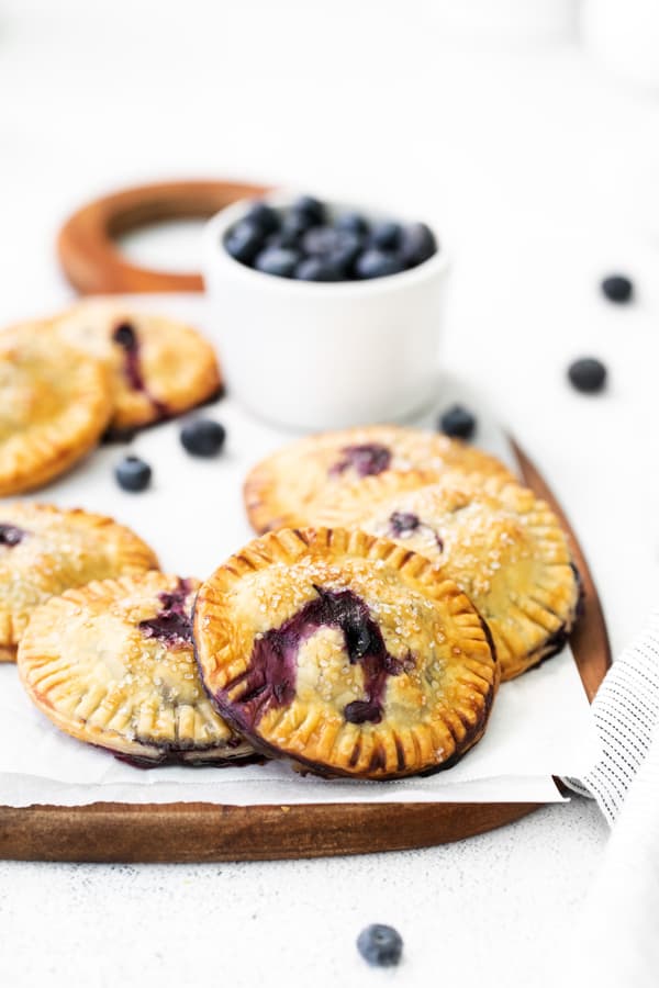 Easy Blueberry Hand Pies on a wooden serving platter sprinkled with coarse sanding sugar. 