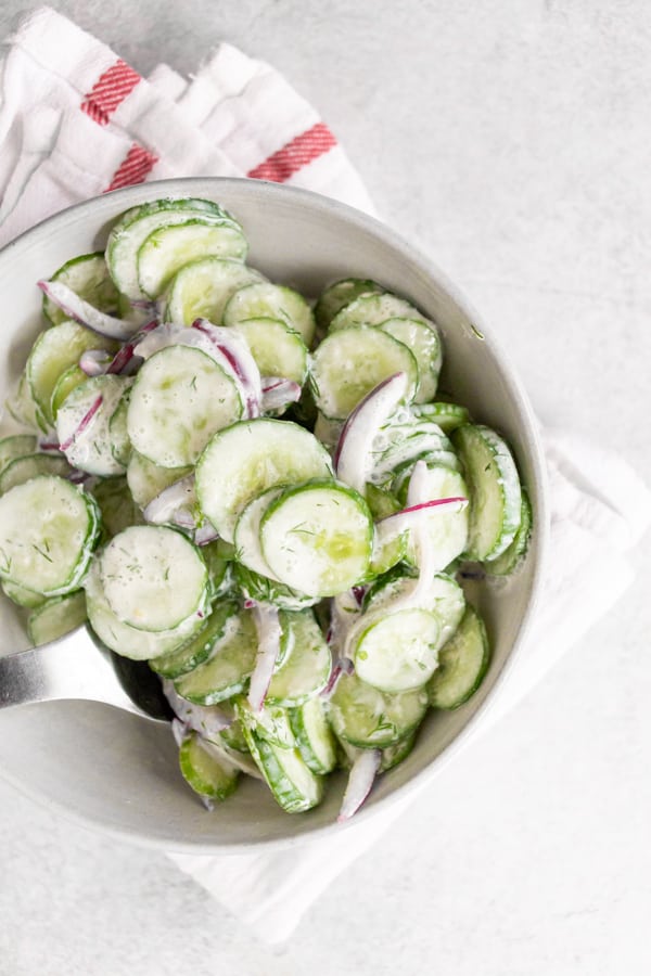 creamy horseradish cucumber salad in a bowl with spoon. 