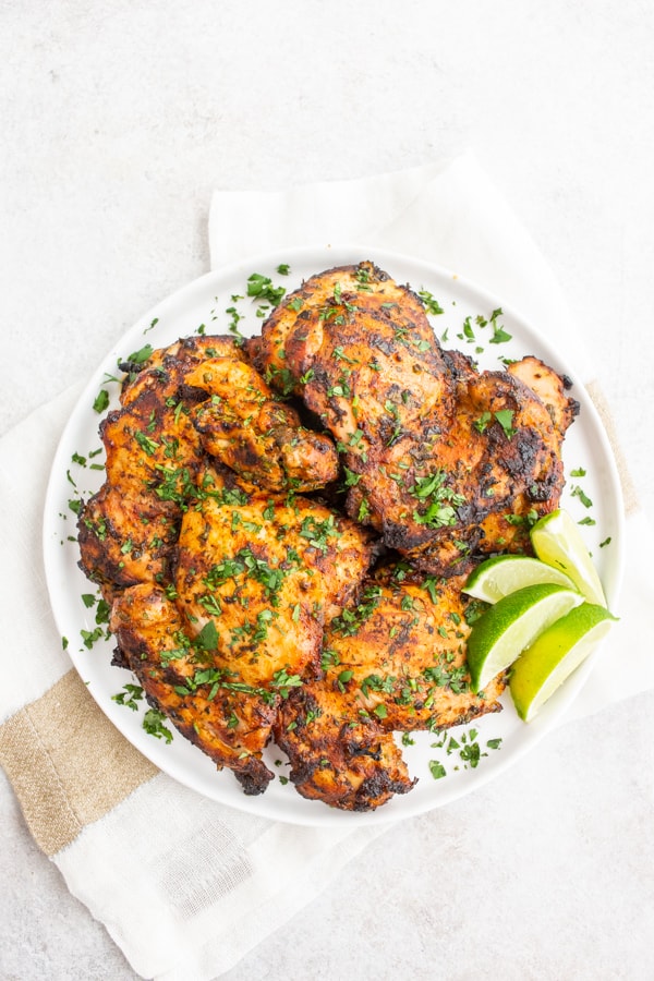 Grilled Cilantro Lime Chicken Thighs served on a plate with cilantro and lime.