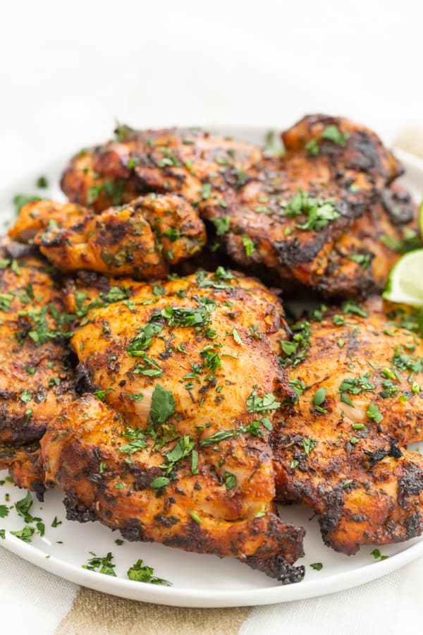 Grilled Cilantro Lime Chicken Thighs on a plate sprinkled with fresh cilantro.