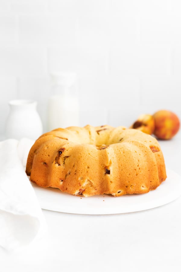 a full Peach Bundt Cake sitting on a marble cake plate. 
