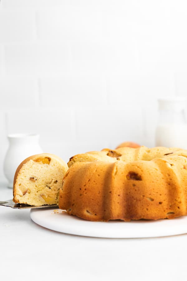 Peach Bundt Cake with a slice being take out of the cake. 